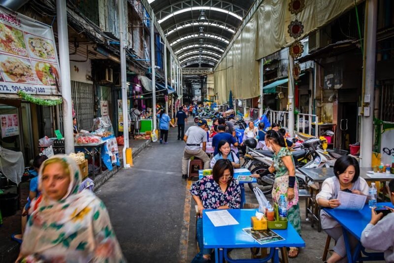 Explore a bustling street market in Chiang Mai, Thailand, with vibrant stalls and diverse crowds.